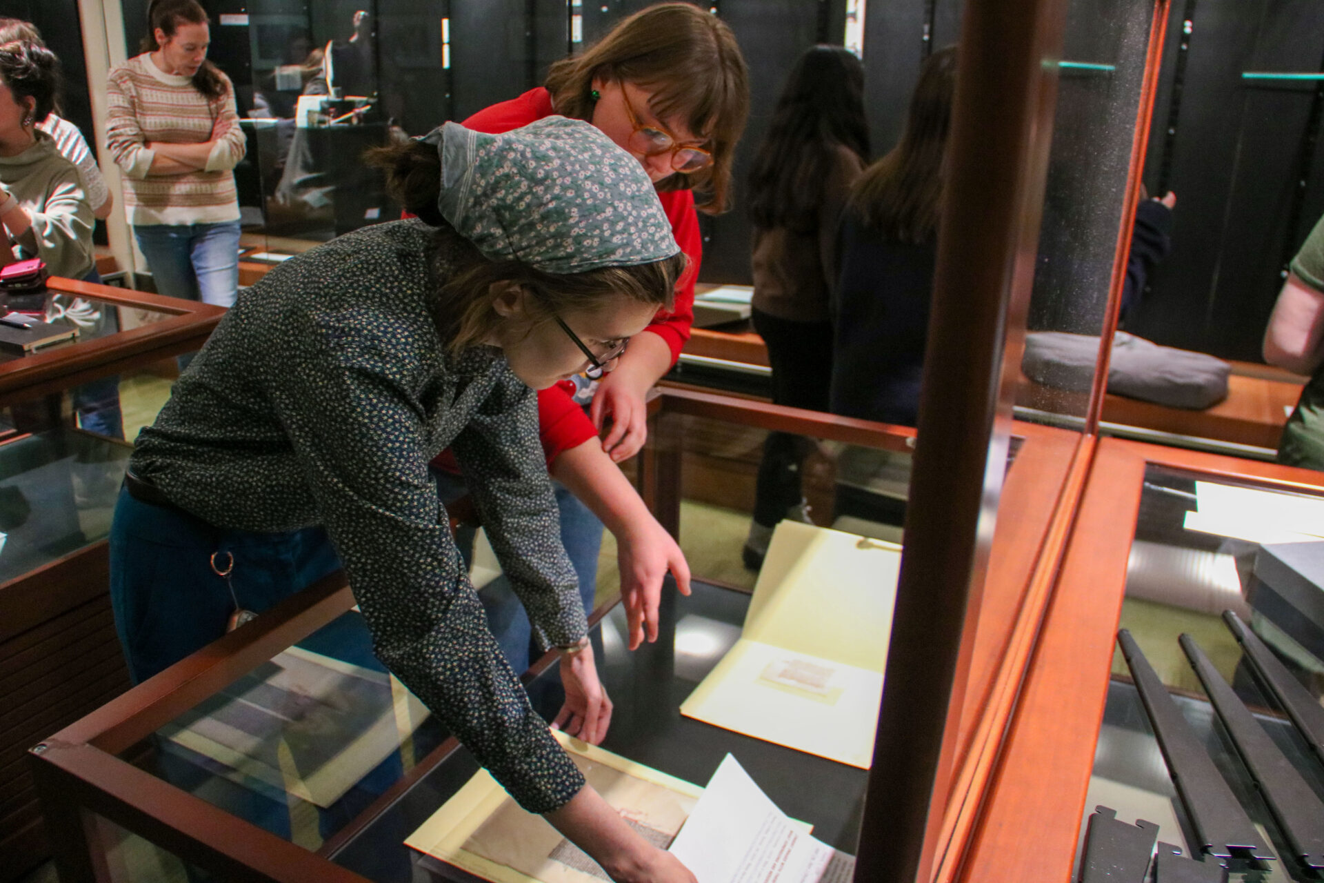 Two students placing archival materials in a glass display case